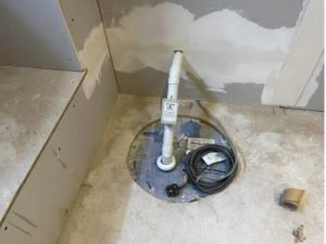 Newly installed sump pump in a pit in the basement floor